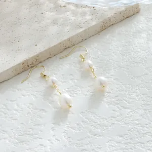 Primer plano detallado de pendientes de oro vintage con perlas barrocas blancas