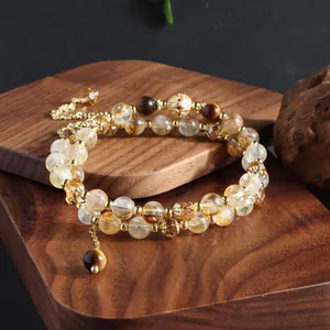 Detailed view of citrine and tiger eye bead bracelet on dark wooden display base