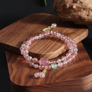 Detailed macro view of a double-strand strawberry quartz beaded bracelet on wood