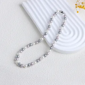 Vue de dessus élégante d'un collier de perles de coquillage coloré sur présentoir blanc