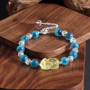 Makroansicht eines blauen Achat- und Kristallarmbands mit gelber Pixiu-Schnitzerei