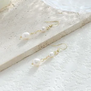 Detalle de pendientes de perlas barrocas naturales con ganchos de oro de 14K sobre piedra