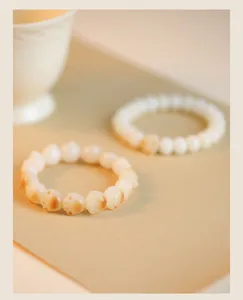 Detail view of toasted cat paw bodhi root bracelets with natural white beads and carvings