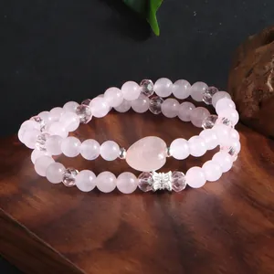 Gros plan détaillé d'un bracelet double couche en quartz rose naturel avec pendentif cœur.