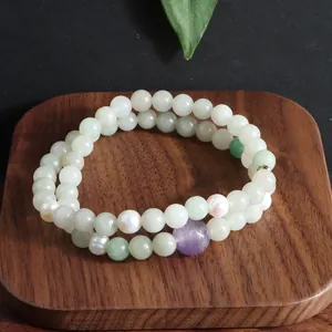 Close-up van dubbele armband met Kunziet-, Aquamarijn kralen en zoetwaterparels op hout