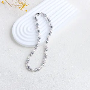 Détail du collier de perles de nacre multicolores sur un support ondulé blanc pur