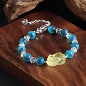 Detailansicht eines blauen Achat-Armbands mit geschnitztem Pixiu auf dunklem Holzsockel