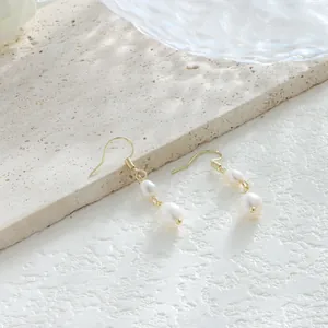 Vista detallada de pendientes bañados en oro de 14K con dos brillantes perlas barrocas