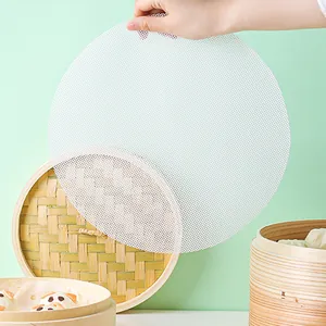 Gros plan d'un tapis de cuisson en silicone blanc tenu au-dessus d'un cuiseur en bambou