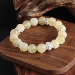 Primer plano detallado de una pulsera de cristal de cuarzo rutilado dorado sobre madera