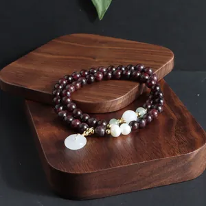 Detailansicht eines zweireihigen Edelsteinarmbands mit Perlen und einem Jade-Anhänger.