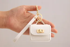 Nahaufnahme eines weißen Mini-Handtaschen-Schlüsselanhängers aus PU-Leder in der Hand