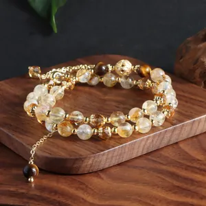 Detailed shot of double-layered yellow citrine and tiger's eye beaded bracelet on wood