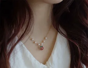 Gros plan d'un collier pendentif pêche en agate Nanhong avec perles d'eau douce et or 14K