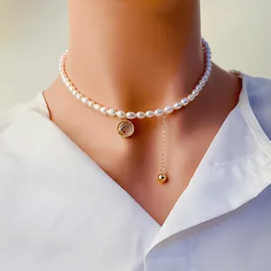 Gros plan détaillé du collier de perles d'eau douce avec pendentif de cerf doré et gland
