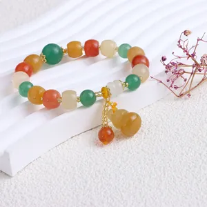 Nahaufnahme eines Goldseiden-Jade-Armbands im ethnischen Stil mit gelbem Kürbis-Anhänger