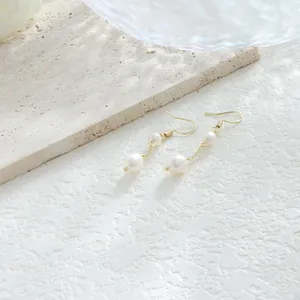 Detalle de pendientes colgantes con perlas barrocas naturales y acabado en oro de 14K.