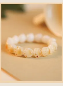 Macro detail of charcoal-baked cat paw shaped beads on a natural bodhi root bracelet