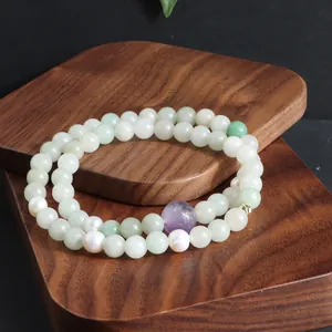 Dubbelstrengs kralenarmband met amethist, jade en parels op een houten standaard