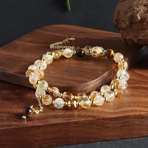 Macro view of double-strand natural citrine and tiger's eye beaded bracelet on wood