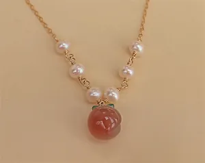 Gros plan détaillé d'un pendentif pêche en agate rouge avec des perles d'eau douce.
