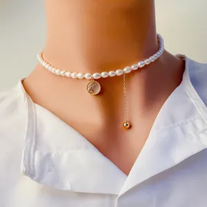 Gros plan d'un collier de perles d'eau douce avec pendentif renne et gland doré