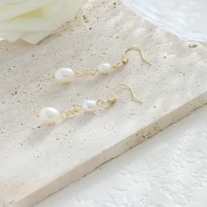 Primer plano de elegantes pendientes de perlas barrocas con acabado en oro de 14 quilates