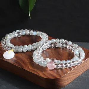 Close-up of natural labradorite and clear quartz crystal double-loop bracelets on wood