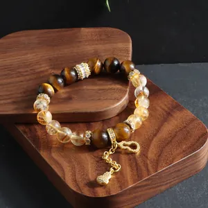 Detailed view of Citrine and Tiger's Eye beaded bracelet with golden gourd charm on wood.