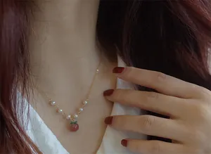 Détail d'un collier avec pendentif pêche en agate rouge et perles d'eau douce élégantes