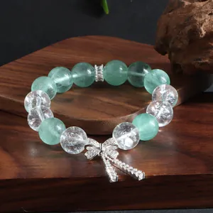 Detailansicht von natürlichem grünem Fluorit und Kristallarmband mit elegantem Schleifenanhänger