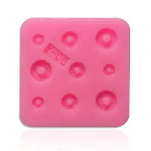 Detailed view of pink silicone mold with various sizes of round dot cavities for baking.