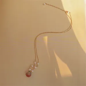 Vue détaillée d'un pendentif pêche en agate rouge et perles sur un collier en or 14K