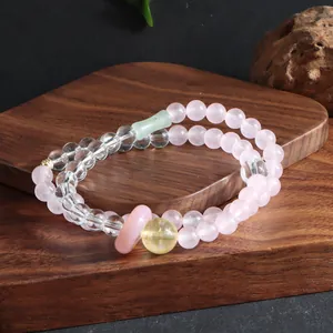 Detailed view of elegant double-strand rose quartz and crystal bracelet on a wooden stand