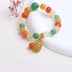 Detailaufnahme eines bunten Jinsi-Jade-Perlenarmbands mit gelbem Flaschenkürbis-Anhänger