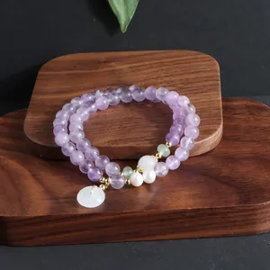 Detailansicht eines zweilagigen Armbands aus lila Amethyst auf einem dunklen Holzbrett