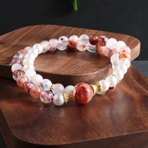 Detail of natural red phantom quartz and pearl double-strand beaded bracelet on wood stand