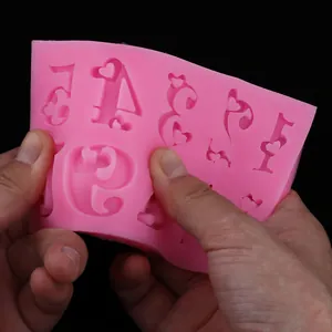 Détail d'un moule flexible en silicone rose pour la décoration de gâteaux DIY en train de plier.