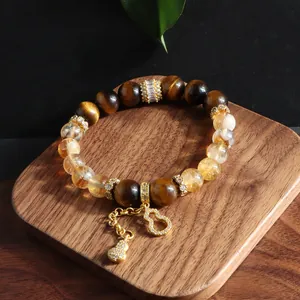 Detail of tiger eye and citrine beaded bracelet with golden gourd charms on wood