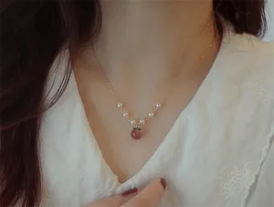 Détail d'un collier en or 14 carats avec pendentif pêche et perles