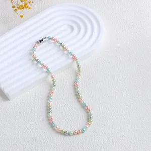 Vue détaillée d'un collier de perles de nacre multicolores sur un plateau blanc.