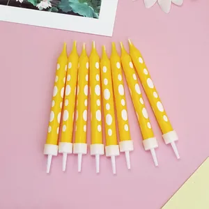 Detailweergave van acht gele verjaardagskaarsen met stippen en witte houders voor feest