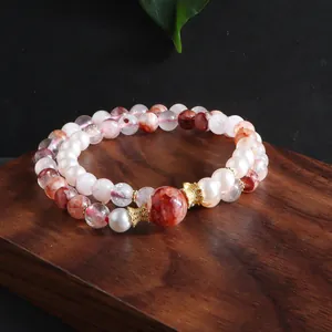 Close-up detail of natural red phantom quartz and pearl beaded bracelet on wood
