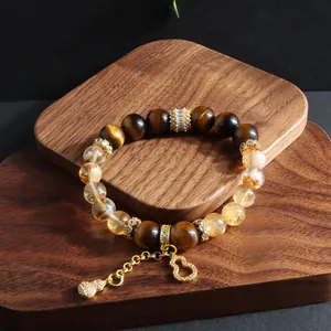 Close-up detail of a tiger eye and yellow crystal bracelet with a golden gourd charm.