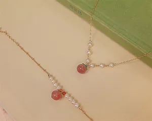 Ensemble collier pêche en agate rouge et bracelet perles d'eau douce finition dorée.