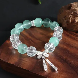 Nahaufnahme eines Armbands aus grünem Fluorit und Kristall mit silbernem Schleifenanhänger