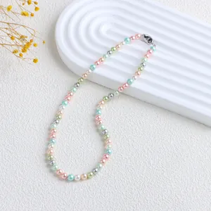 Gros plan d'un collier de perles aux couleurs de bonbons sur un fond blanc texturé