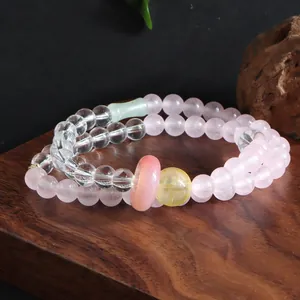 Elegant double-strand rose quartz and citrine crystal beaded bracelet on a rustic wooden base
