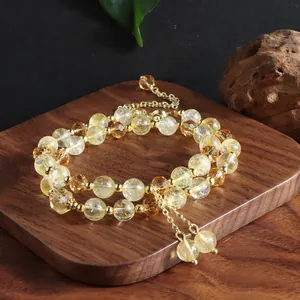 Close-up of double-strand yellow citrine crystal bracelet with gold tassel on wood