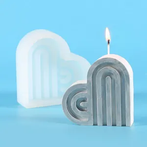 Close-up of heart-shaped arch candle with silicone mold on light blue background